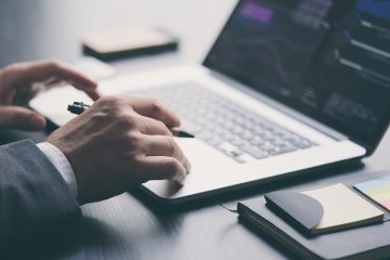 Businessman working on laptop and analysing the financial information at his office. Close up of male hands typing on computer keyboard