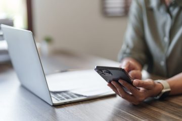 Close up woman working on laptop and using mobile phone in office.